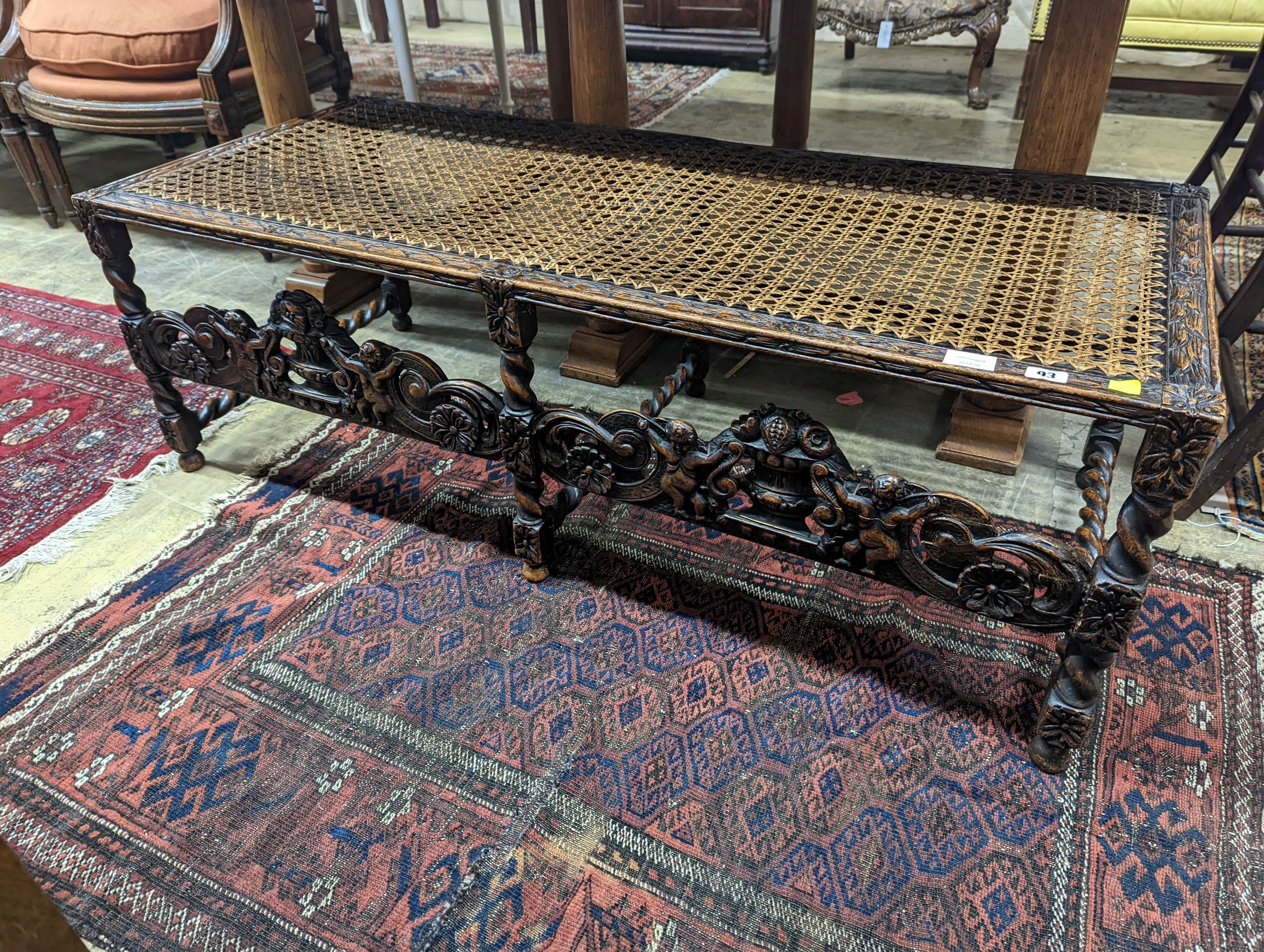 A 1920's Carolean style oak and cane work window seat, length 130cm, depth 58cm, height 44cm